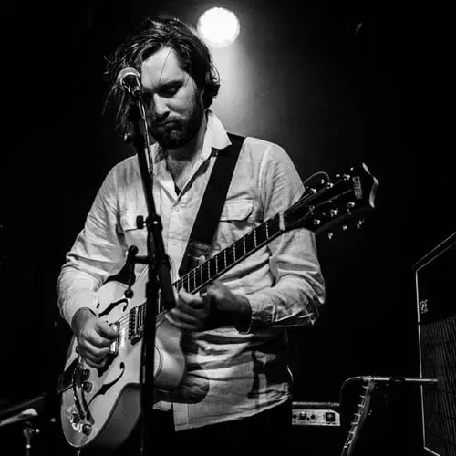 Black-and-white photo of a musician playing guitar under a spotlight